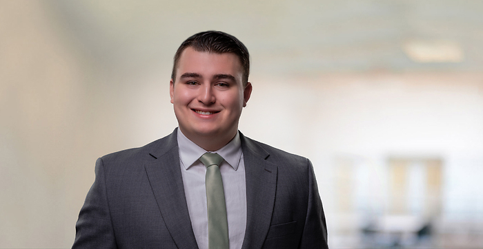 Man with sage tie and gray suit on champagne colored background