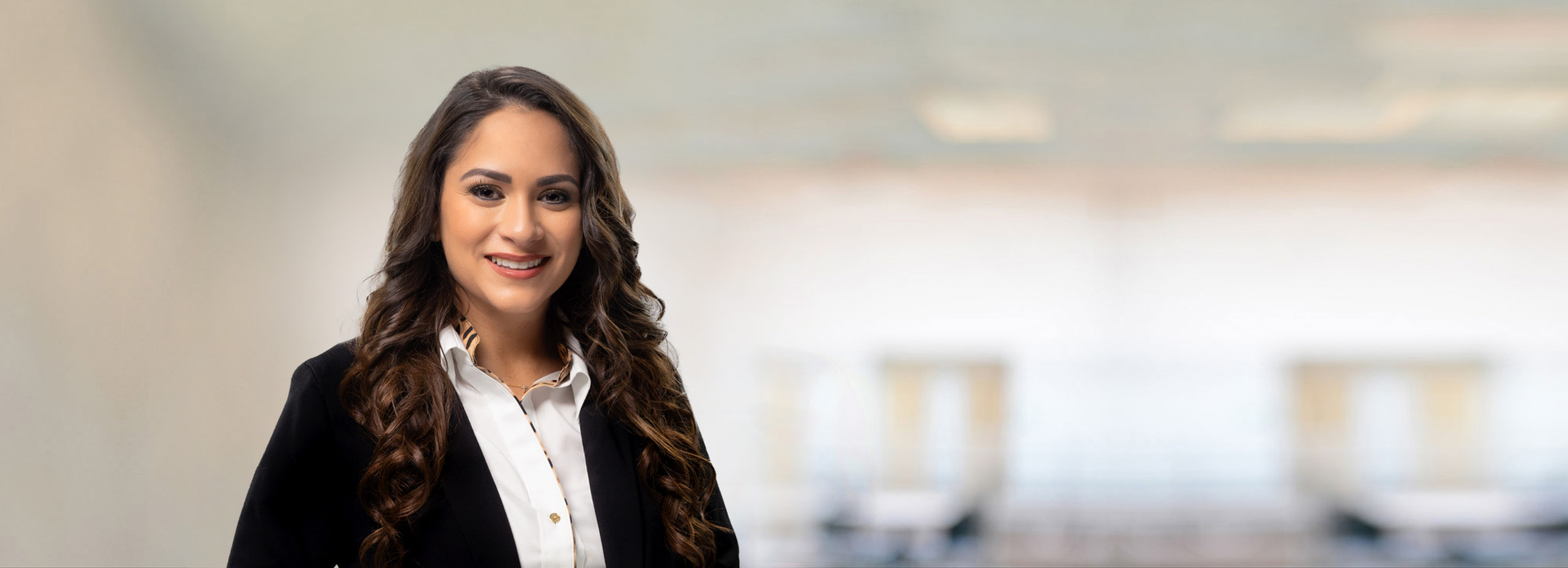 Professional photo of woman smiling with curly brown hair wearing a black blazer jacket